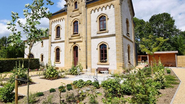 A historic building with a symmetrical facade, multiple arched windows, and a central tower. - Beautiful Villa With Sauna in Chiny (Chiny)