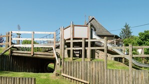 A wooden play structure with a slide and a small bridge. - Spacious Holiday Home With Large Garden (Amel)