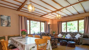 A dining area with a table set for four, surrounded by wooden chairs, a sofa, and a cushioned bench. - Spacious Holiday Home With Large Garden (Amel)
