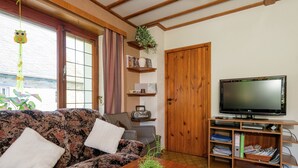 A living room with a sofa, a coffee table, a television, and a bookshelf. - Spacious Holiday Home With Large Garden (Amel)