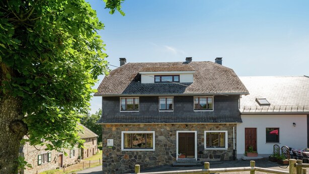 A stone house with a two-story structure, a wooden fence in the foreground, and a clear sky. - Spacious Holiday Home With Large Garden (Amel)