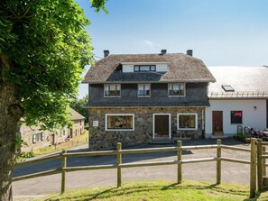 A stone house with a two-story structure, a wooden fence in the foreground, and a clear sky. - Spacious Holiday Home With Large Garden (Amel)