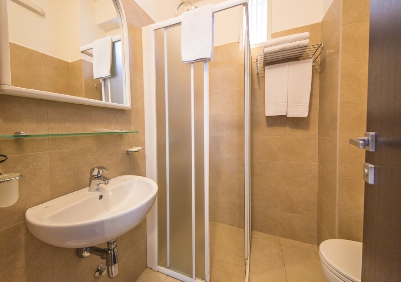 Une salle de bain avec une douche à parois de verre, un lavabo blanc et des toilettes.