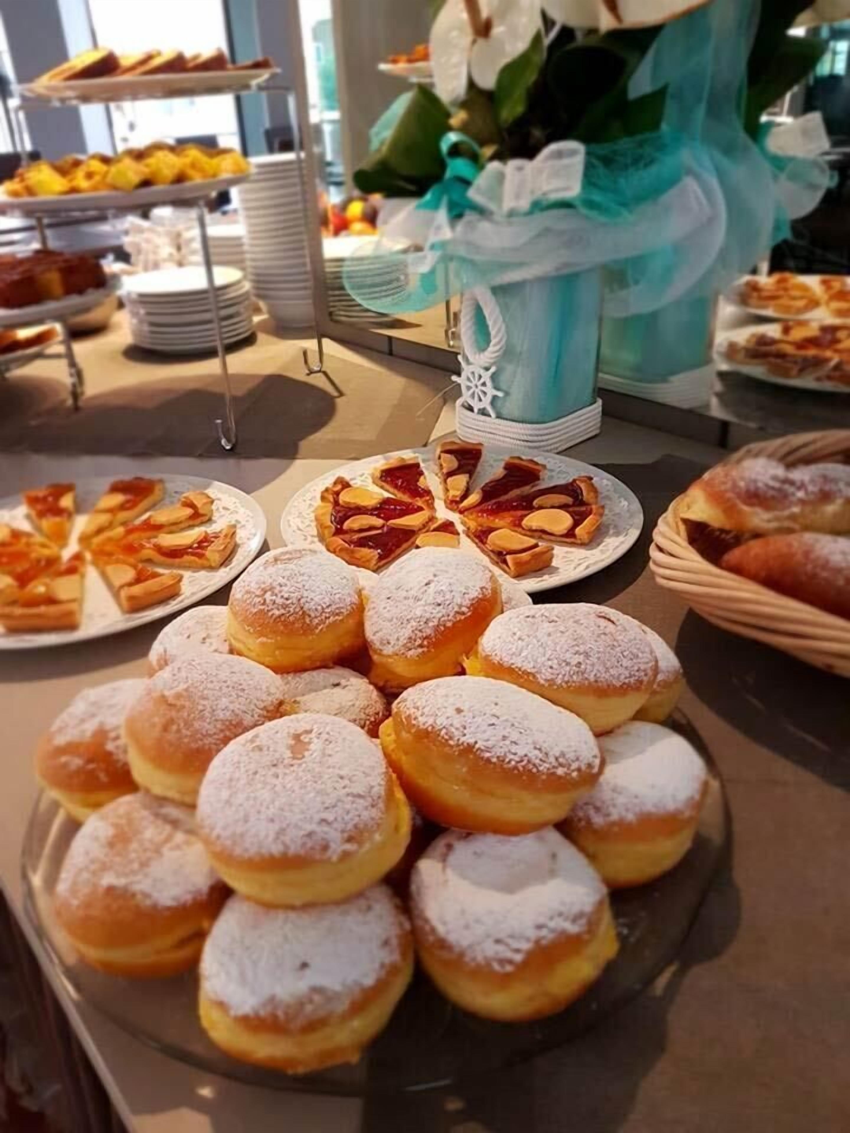Un bufé con diversos pasteles, incluyendo rosquillas y tartas.