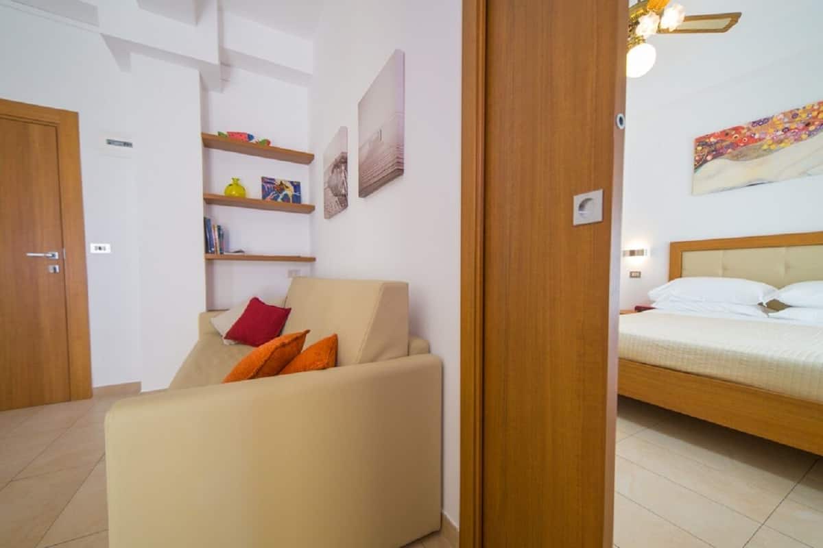 Een moderne woonkamer met een bank, een bed en een houten deur.