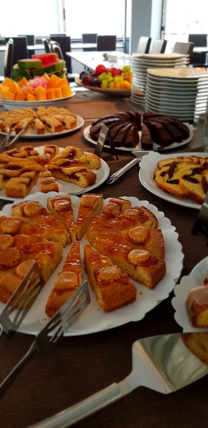 A buffet table with various food items including cakes, fruits, and a chocolate dessert.