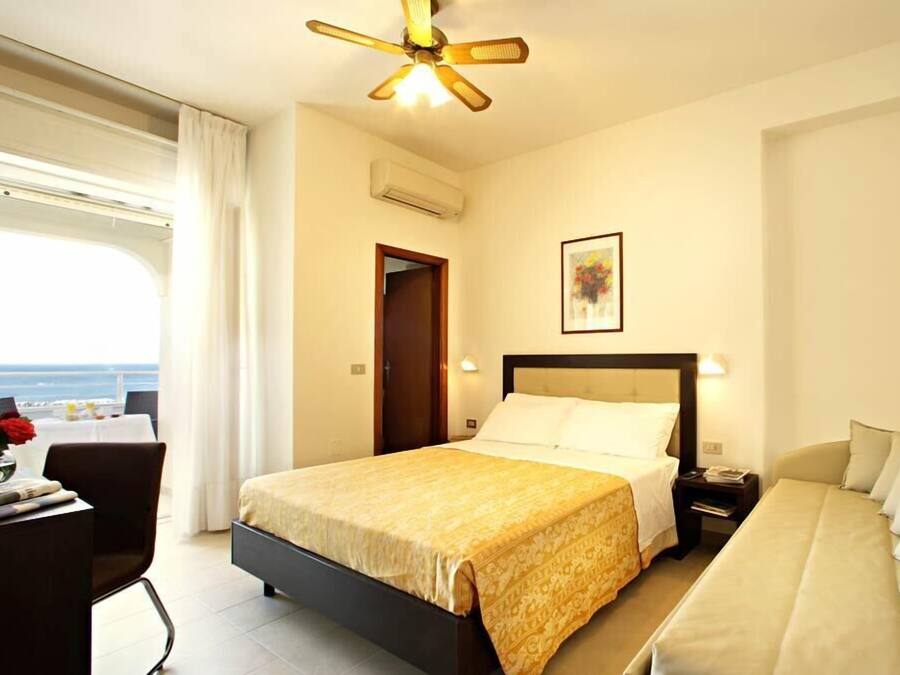 Ein Hotelzimmer mit Bett, Nachttisch und Meerblick.