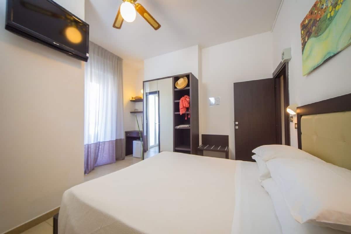 Een hotelkamer met een bed, een kledingkast, een bureau en een televisie.