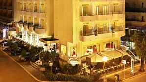Un hôtel à plusieurs étages doté de balcons, d’un espace extérieur aménagé et d’une façade bien éclairée.