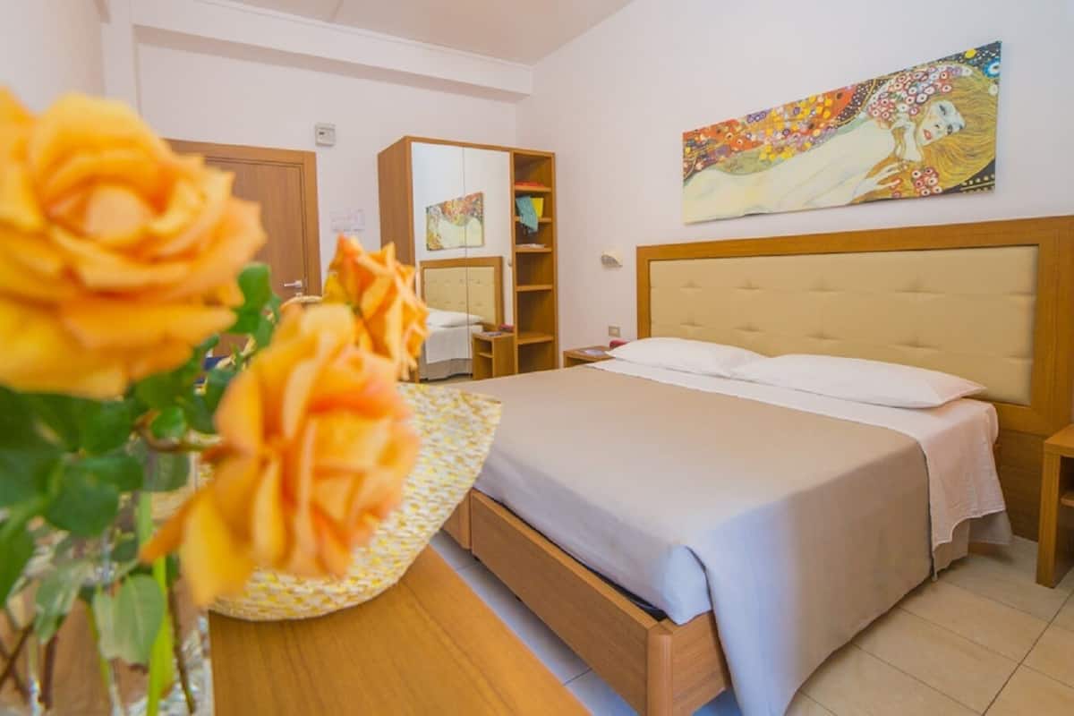 Een hotelkamer met een bed, nachtkastjes, een kledingkast en een schilderij aan de muur.