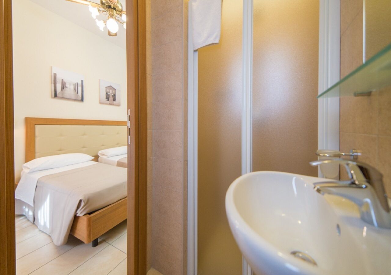 Una habitación de hotel con cama, baño con lavamanos y espejo.