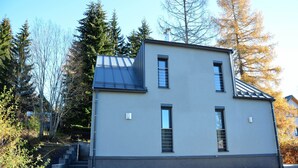 A two-story building with a flat roof, a small window on the second floor, and a staircase leading to the entrance. - Quaint Holiday Home in Železná Ruda near Ski Area (Zelezna Ruda)