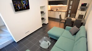 A modern living room with a teal sofa, a glass coffee table, and a TV mounted on the wall. - Quaint Holiday Home in Železná Ruda near Ski Area (Zelezna Ruda)