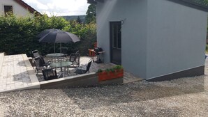 A small outdoor patio with a table and chairs, a black umbrella, and a barbecue grill. - Quaint Holiday Home in Železná Ruda near Ski Area (Zelezna Ruda)