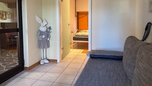 A living room with a sofa, a door leading to a bedroom, and a stuffed rabbit decoration. - Grosses Ferienhaus Fuer 8 Personen, Manderscheid (Manderscheid)