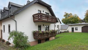 A two-story house with a balcony, a small garden, and a garage. - Eschfeld Sauna Apartment (Eschfeld)
