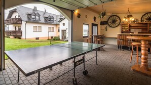 An indoor ping pong table with a view of a house through an archway. - Eschfeld Sauna Apartment (Eschfeld)
