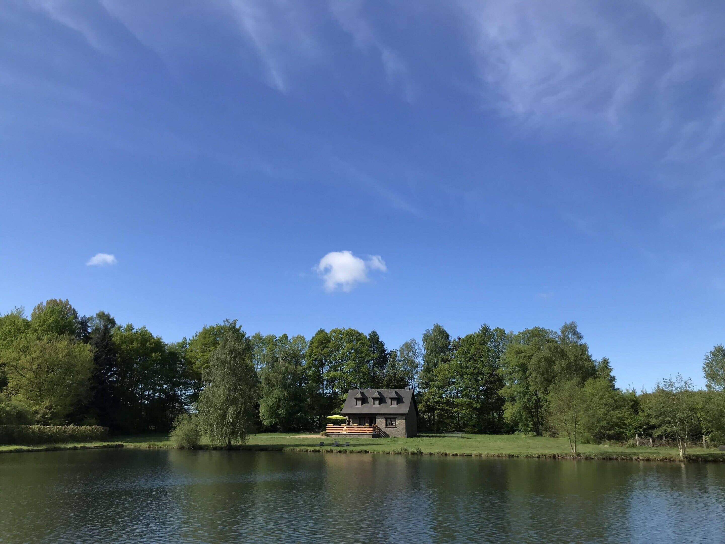 A lakeside house with a dock, surrounded by trees and a clear sky.