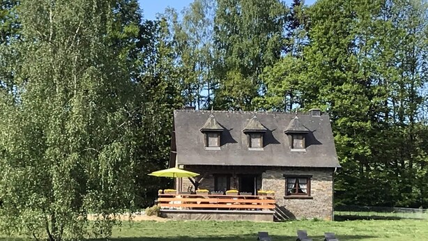 A stone house with a sloped roof, a wooden deck, and a bench. - Lakeside Getaway in Bouillon (Paliseul)