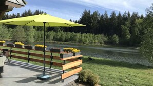 An outdoor seating area with a bench and a yellow umbrella, overlooking a lake surrounded by trees. - Lakeside Getaway in Bouillon (Paliseul)
