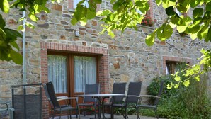 A stone building with a patio area featuring outdoor seating. - Vintage Home With Pets (Daverdisse)