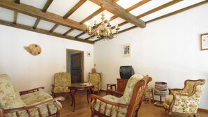 A room with wooden beams, a chandelier, floral-patterned chairs, a television, and a door. - Vintage Home With Pets (Daverdisse)