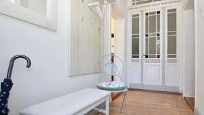 Un petit espace de véranda fermé, comprenant un banc, une chaise et un parasol en métal.