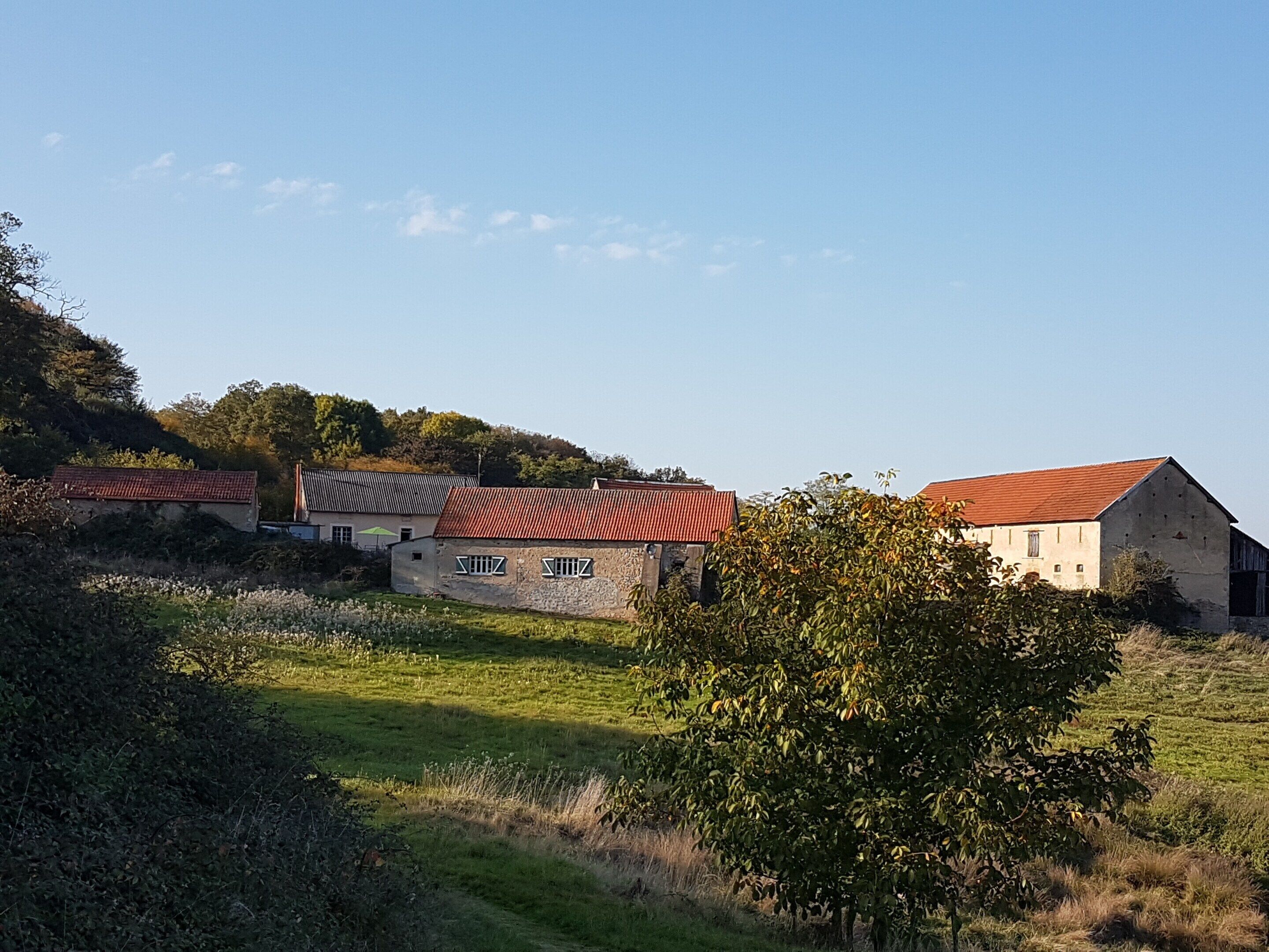 Entorno rural con edificios de piedra, un granero y un campo cubierto de hierba.