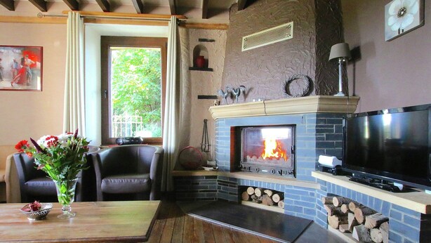 A cozy living room with a fireplace, a television, and a dining area with a table and chairs. - Spacious Country Villa (Neufchateau)