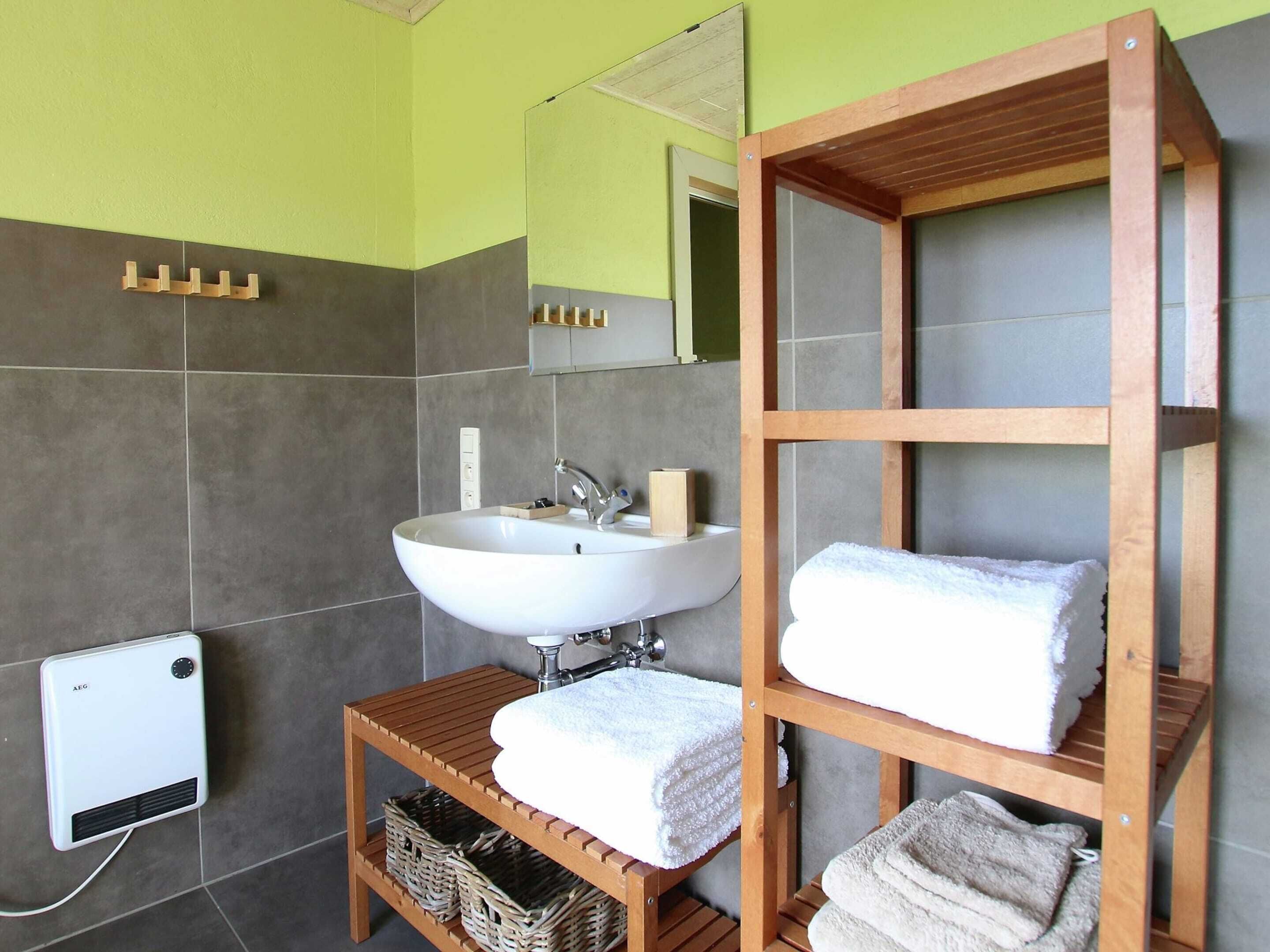 A bathroom with a white sink, wooden shelves, and a mirror.