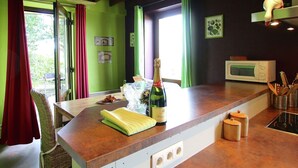 A kitchen with a wooden countertop, a microwave, a bottle of champagne, and a wicker chair. - Spacious Country Villa (Neufchateau)