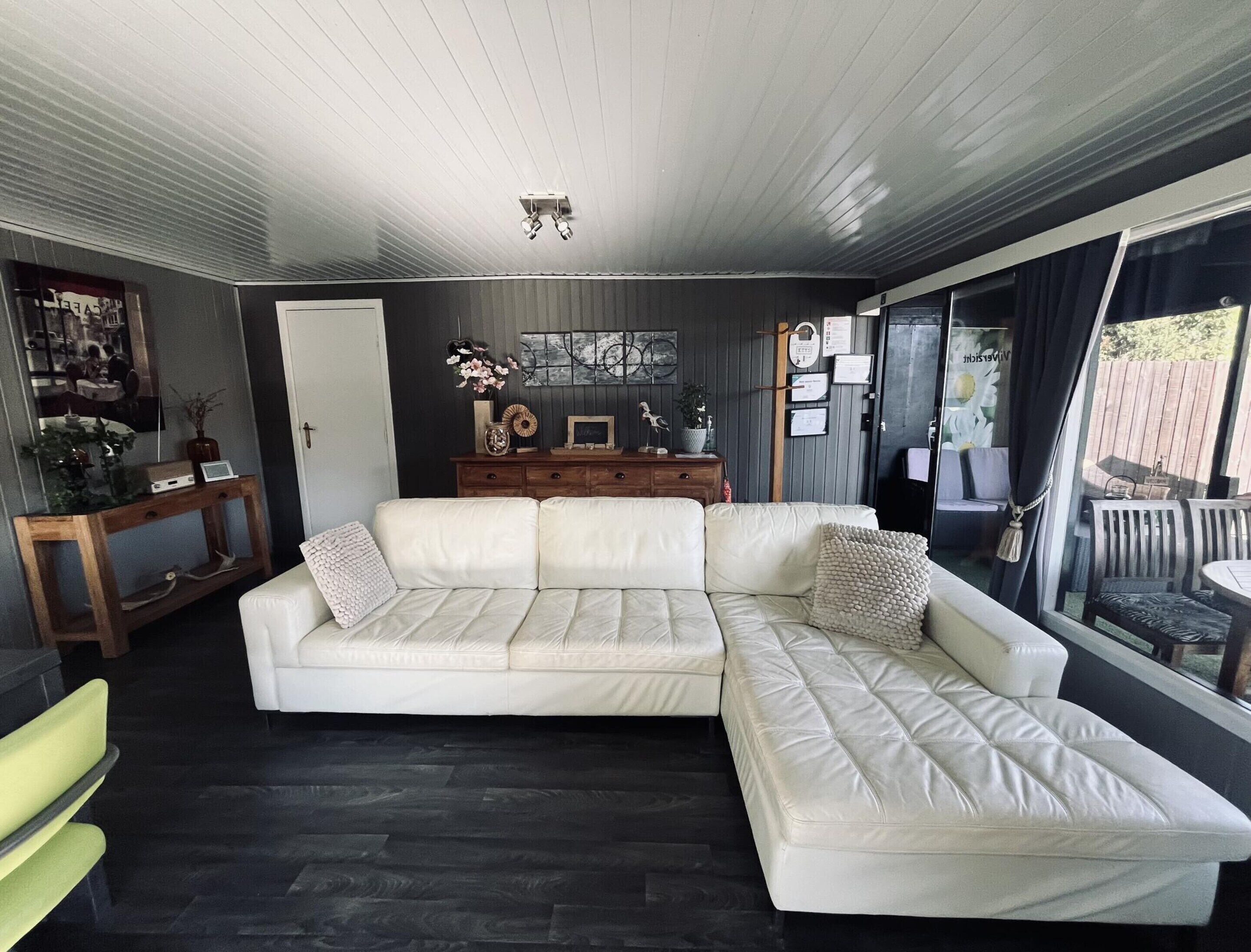 A modern living room with a sectional sofa, a wooden console table, and a large window with curtains.