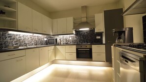 Een moderne keuken met witte kasten, een inbouwoven, een magnetron en een gasfornuis.