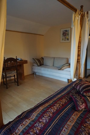 Un dormitorio con cama, sofá, escritorio y silla.