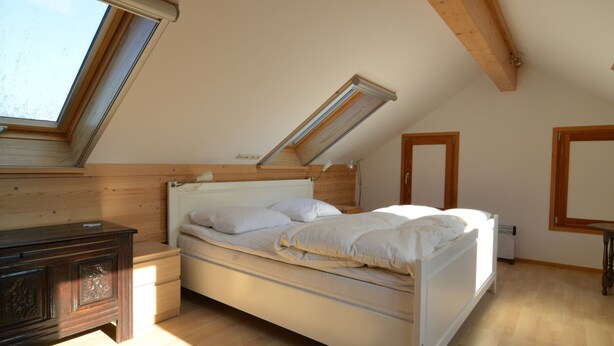 A bedroom with a sloped ceiling, a bed, a nightstand, a dresser, and a window. - Holiday Home in Izier With Roofed Terrace, Garden, Parking (De Panne)