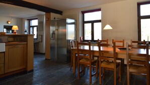 A spacious kitchen with a dining area, featuring a large island, a refrigerator, and a window providing natural light. - Holiday Home in Izier With Roofed Terrace, Garden, Parking (De Panne)