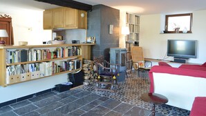 A cozy living room with a fireplace, bookshelves, a TV, and a red sofa. - Holiday Home in Izier With Roofed Terrace, Garden, Parking (De Panne)