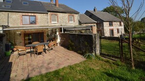 A stone house with a patio, a dining area, and a covered outdoor space. - Holiday Home in Izier With Roofed Terrace, Garden, Parking (De Panne)