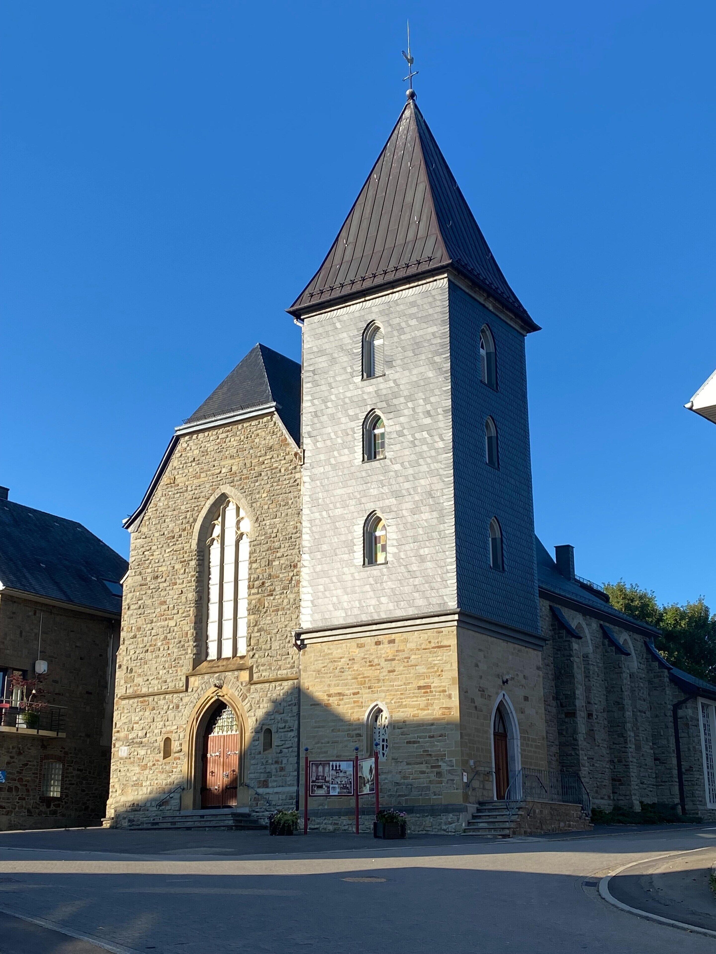 A church with a stone facade, a bell tower, and a large arched entrance.