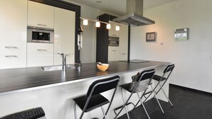 A modern kitchen with a central island, stainless steel appliances, and a black and white color scheme. - Villa in Luttenberg Near National Park (Luttenberg)