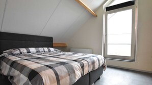 A bedroom with a bed, a window, and a sloped ceiling. - Villa in Luttenberg Near National Park (Luttenberg)
