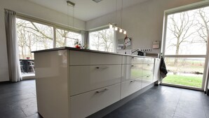 A modern kitchen with a large island, large windows, and a view of the outdoors. - Villa in Luttenberg Near National Park (Luttenberg)