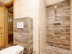 A bathroom with a wooden vanity, a toilet, and a shower area with a wooden wall and a showerhead. - Modern Holiday Home in Meyerode With Terrace (Amel)