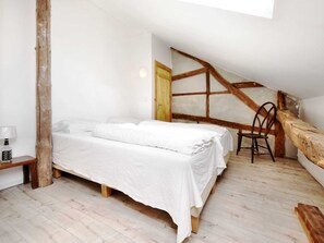 A bedroom with a bed, a chair, a nightstand, and a wooden beam structure. - Modern Holiday Home in Meyerode With Terrace (Amel)