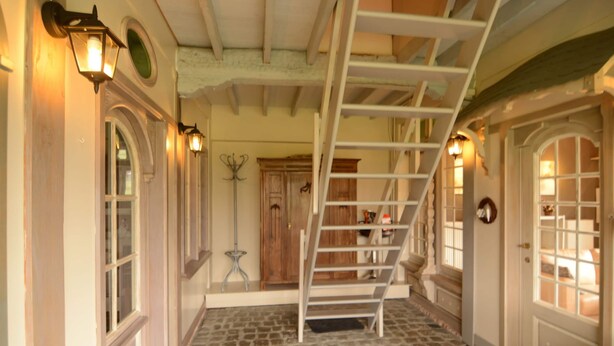 A stone-floored interior with a wooden staircase, a coat rack, and a door with a glass panel. - Holiday Home in Zele Near Laarne Castle (Zele)