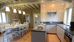 A kitchen with a central island, white cabinetry, and a dining area with chairs and a table. - Holiday Home in Zele Near Laarne Castle (Zele)