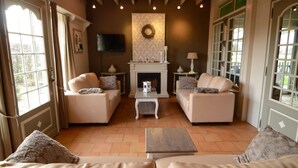 A living room with two sofas, a coffee table, a fireplace, and a television. - Holiday Home in Zele Near Laarne Castle (Zele)