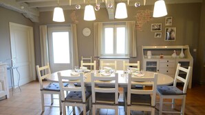A dining area with a round table, six chairs, and hanging pendant lights. - Holiday Home in Zele Near Laarne Castle (Zele)
