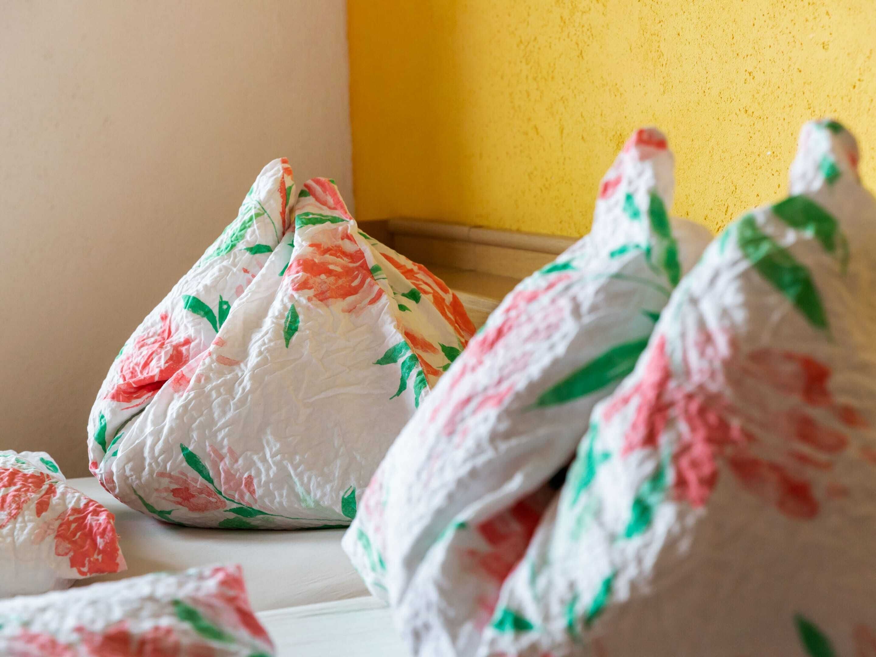 A bed with floral-patterned bedding and a yellow wall in the background.