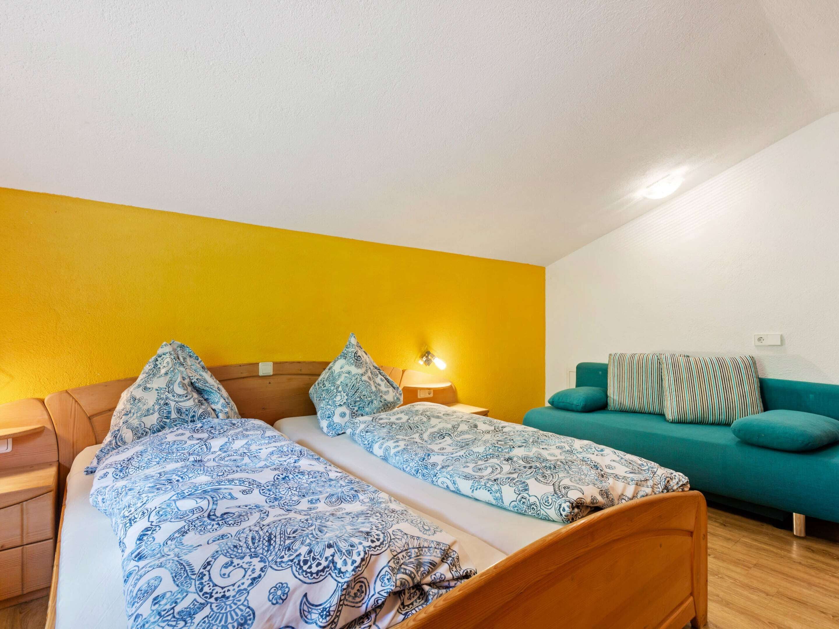 A bedroom with two beds, a sofa, and a nightstand.